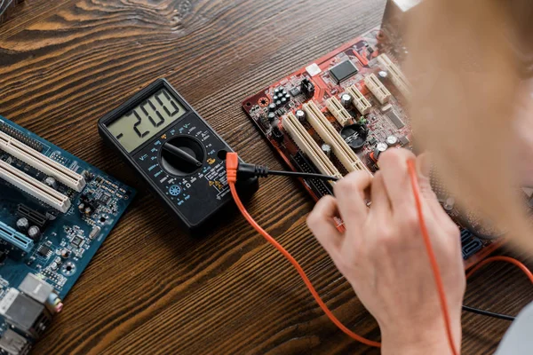 Schnappschuss von Elektrotechniker mit Tester untersucht Motherboard — Stockfoto