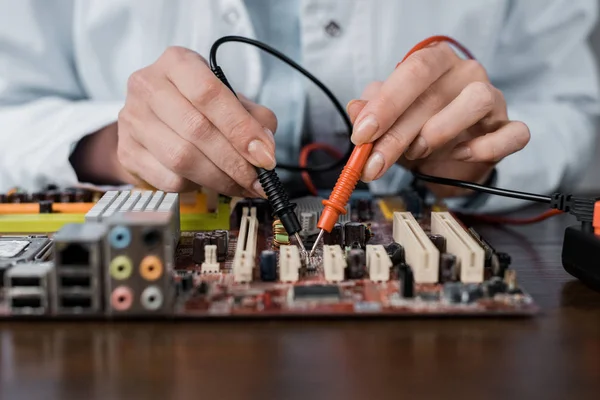Cropped shot of computer engineer with tester examining motherboard — Stock Photo