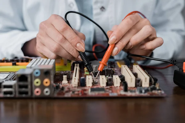 Tiro recortado de engenheiro de computação com testador examinando placa-mãe — Fotografia de Stock