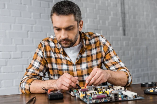 Engenheiro de computação concentrado com testador examinando placa-mãe — Fotografia de Stock