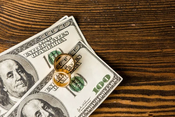 Vista superior de dinheiro e anéis de casamento na mesa de madeira — Fotografia de Stock