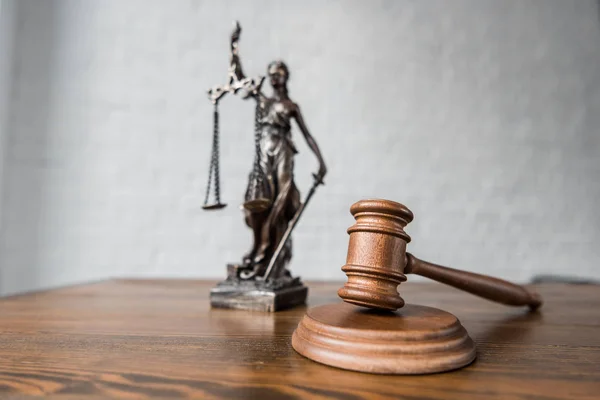 Close-up shot of judge gavel and themis statue on wooden table — Stock Photo