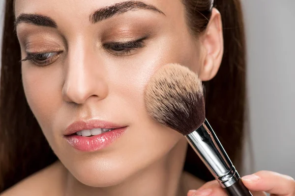 Attractive girl applying powder on face with cosmetic brush — Stock Photo