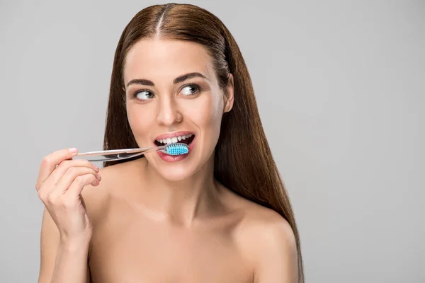 Bela mulher com escova de dentes na boca isolada em cinza — Fotografia de Stock