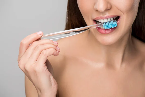 Обрізаний вид жінки з зубною щіткою в роті ізольовано на сірому — стокове фото