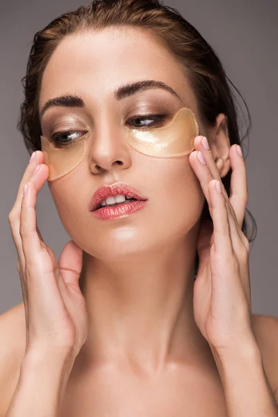 Elegante mujer joven con parches de ojo dorado, aislado en gris - foto de stock