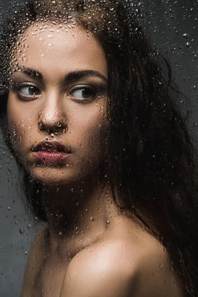 Mulher morena atraente atrás de vidro molhado no chuveiro — Fotografia de Stock
