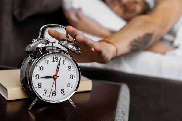 Vista da vicino del giovane che spegne la sveglia mentre si sveglia la mattina — Foto stock