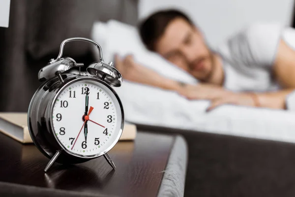 Close-up view of alarm clock and young man sleeping behind — Stock Photo