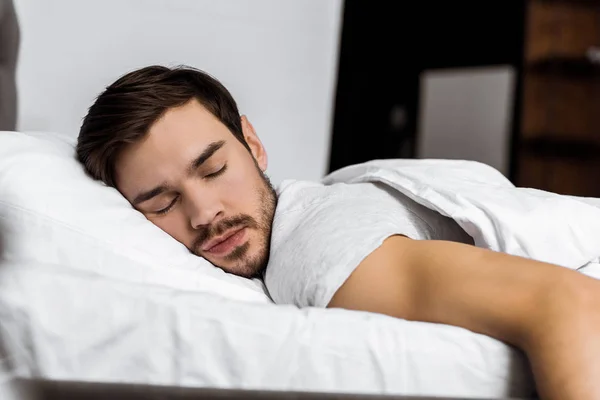 Красивый бородатый молодой человек, спящий в постели дома — стоковое фото