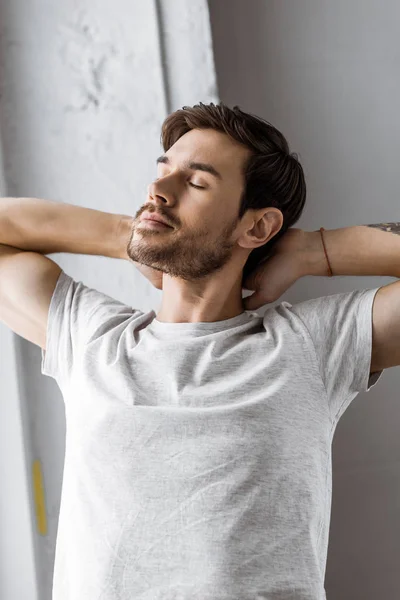 Handsome young man with closed eyes stretching in the morning — Stock Photo