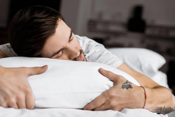 Guapo joven tatuado hombre durmiendo en la cama - foto de stock