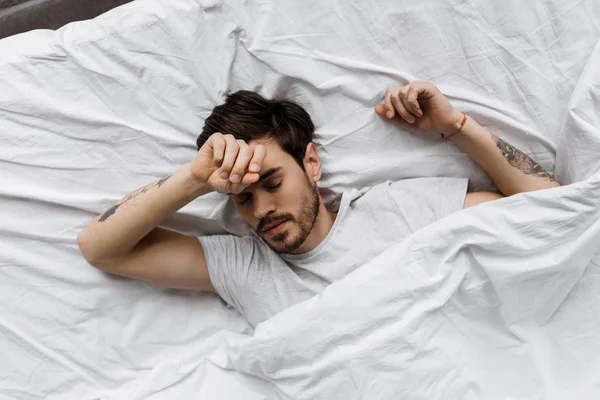 Draufsicht auf schlafenden jungen Mann, der zu Hause unter Decke im Bett liegt — Stockfoto