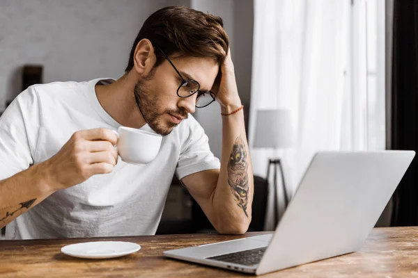 Überarbeitete junge Freiberuflerin mit Kaffee am heimischen Laptop-Bildschirm — Stockfoto