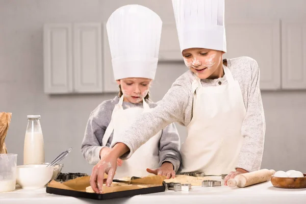 Adorable soeur et son frère mettre de la pâte pour les biscuits sur plaque de cuisson dans la cuisine — Photo de stock