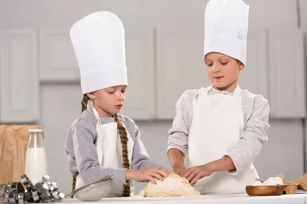 Adorabili bambini che preparano la pasta per i biscotti a tavola in cucina — Foto stock