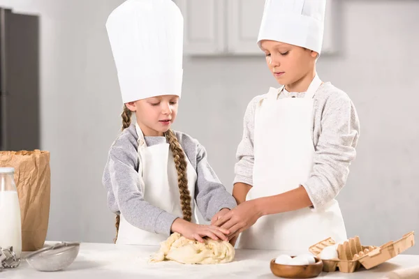 Selective focus of brother and sister preparing dough for cookies at table in kitchen — Stock Photo