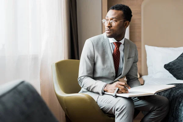 Belo empresário afro-americano com diário no quarto de hotel — Fotografia de Stock