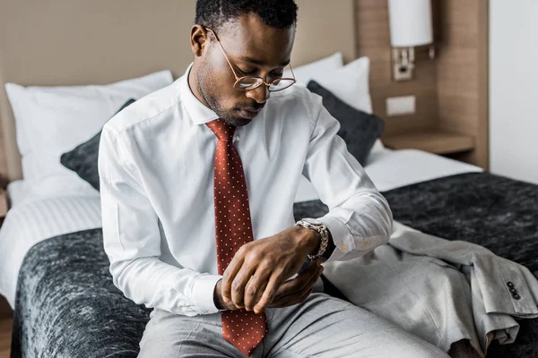 Elegant businessman in formal wear and red tie wearing wristwatch — Stock Photo