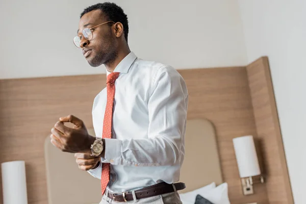 Handsome african american businessman wearing wristwatch in hotel room — Stock Photo