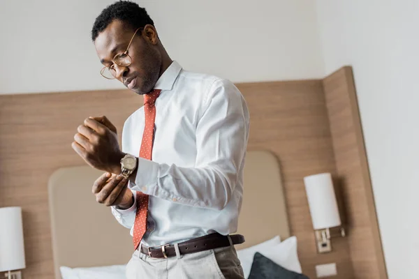 Homme d'affaires afro-américain portant une montre-bracelet dans la chambre d'hôtel — Photo de stock