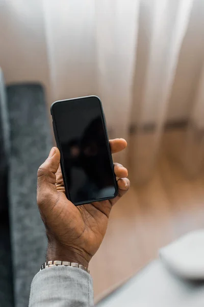 Vista recortada del hombre afroamericano utilizando un teléfono inteligente con pantalla en blanco - foto de stock