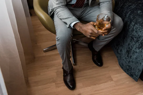 Vista cortada de homem afro-americano segurando copo de uísque — Fotografia de Stock