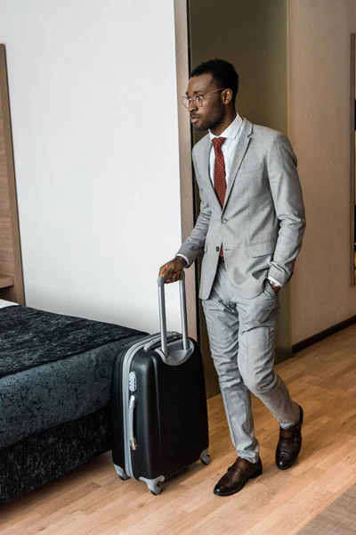 Hombre de negocios afroamericano con bolsa de viaje que entra en la habitación de hotel - foto de stock