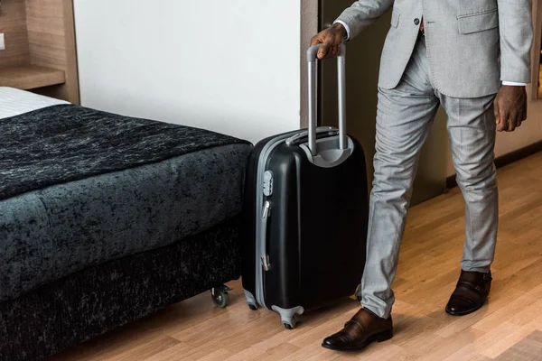 Vista recortada de hombre de negocios con bolsa de viaje en la habitación de hotel - foto de stock