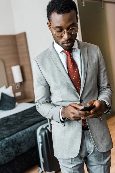 Красивий афроамериканський бізнесмен використовує смартфон у готельному номері — стокове фото