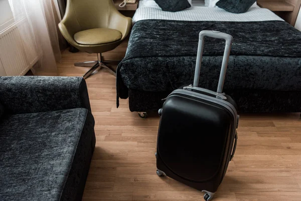 Black suitcase for travel in hotel room with bed and armchair — Stock Photo