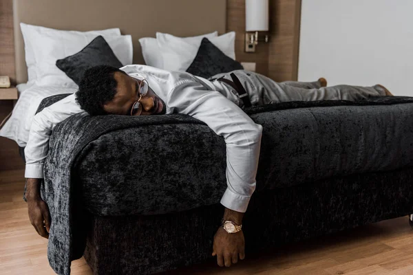 Exausto afro-americano dormindo na cama no quarto de hotel — Fotografia de Stock