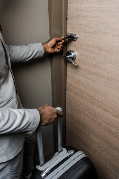 Cropped view of businessman with suitcase opening door with electronic key in hotel — Stock Photo