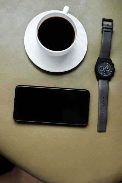 Vue du haut de tasse de café, montre-bracelet et smartphone avec écran blanc — Photo de stock