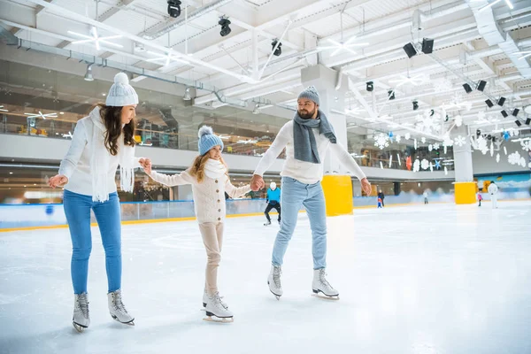 Familia feliz tomados de la mano mientras patinan juntos en pista de hielo - foto de stock