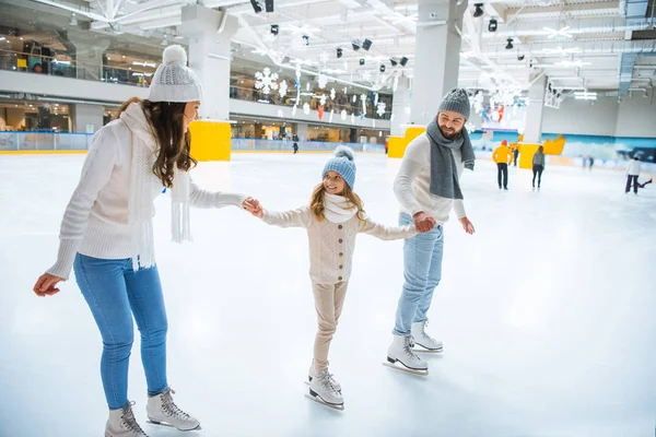 Happy family holding hands while skating together on ice rink — Stock Photo
