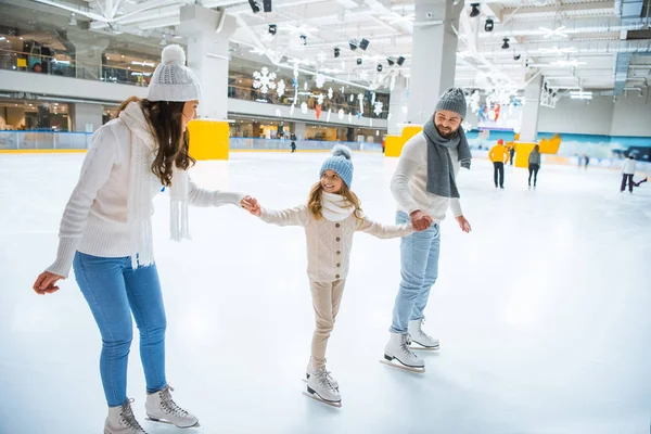 Família feliz de mãos dadas enquanto patinam juntos na pista de gelo — Fotografia de Stock