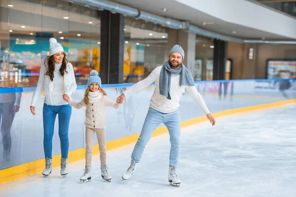 Familia feliz tomados de la mano mientras patinan juntos en pista de hielo - foto de stock