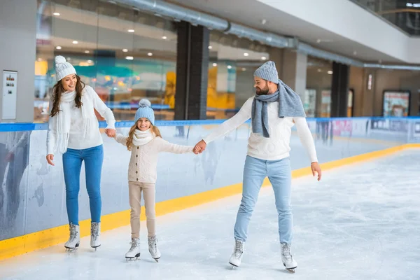 Fröhliche Familie in Pullovern hält Händchen beim gemeinsamen Schlittschuhlaufen auf der Eisbahn — Stockfoto