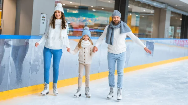 Familia feliz tomados de la mano mientras patinan juntos en pista de hielo - foto de stock