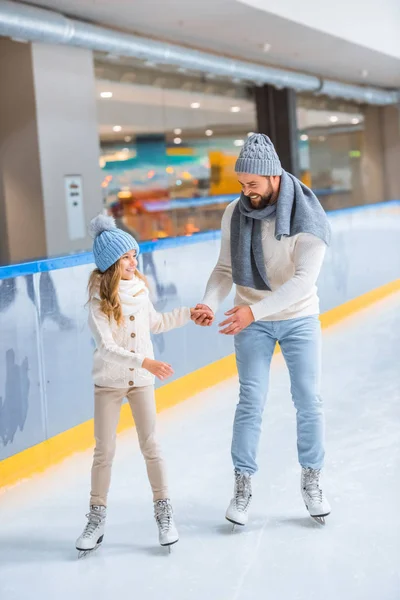 Батько і дочка в трикотажних светрах катаються на ковзанах разом — стокове фото