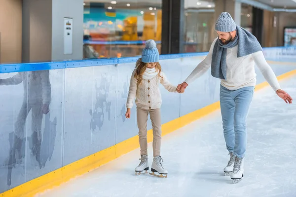 Vater und Tochter in Strickpullovern laufen gemeinsam auf Eisbahn — Stockfoto