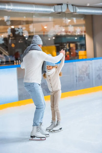 Батько і дочка в трикотажних светрах катаються на ковзанах разом — стокове фото