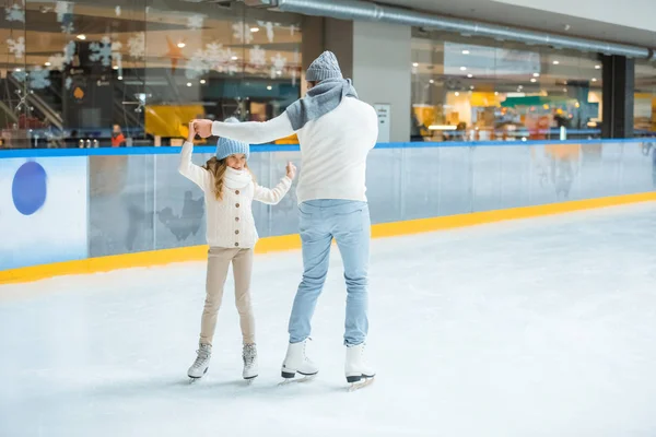 Батько і дочка тримаються за руки під час катання разом на ковзанах — стокове фото