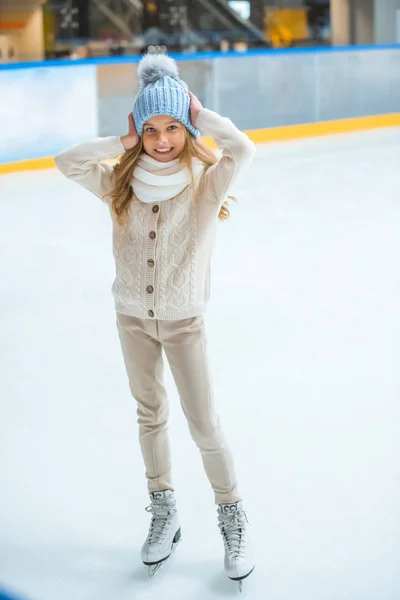 Улыбающийся очаровательный ребенок в свитере и шляпе на катке — стоковое фото