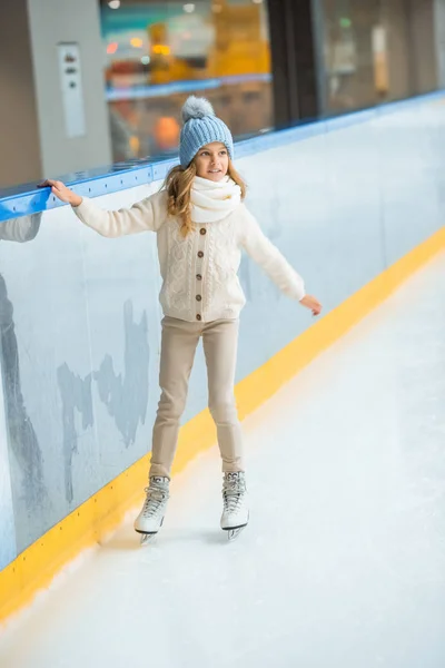 Little child in knitted hat and sweater skating on ice rink — Stock Photo