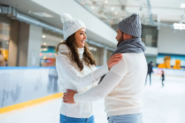 Vista laterale di coppia romantica sorridente sulla pista di pattinaggio — Foto stock