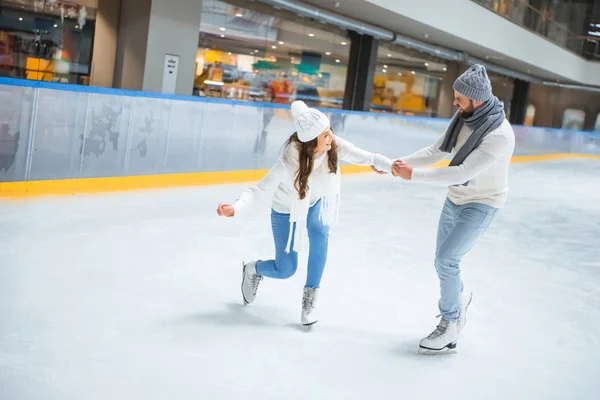 Hombre enseñando novia cómo patinar en pista de hielo - foto de stock