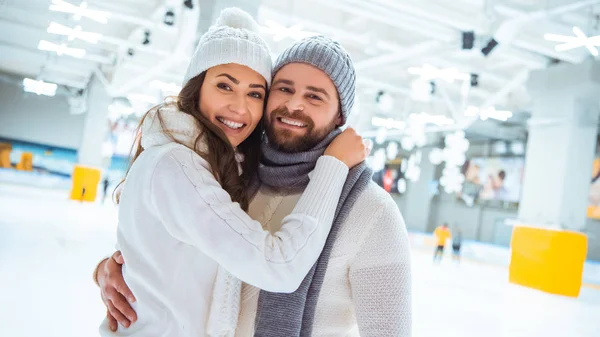 Portrait of happy couple hugging and looking at camera on skating rink — Stock Photo