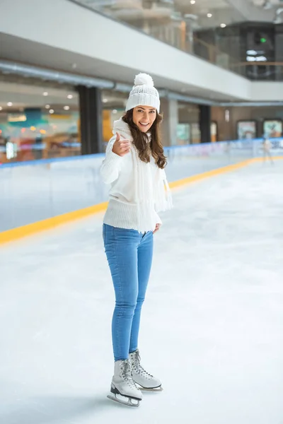 Jovem mulher feliz mostrando polegar para cima enquanto patina na pista de gelo — Fotografia de Stock